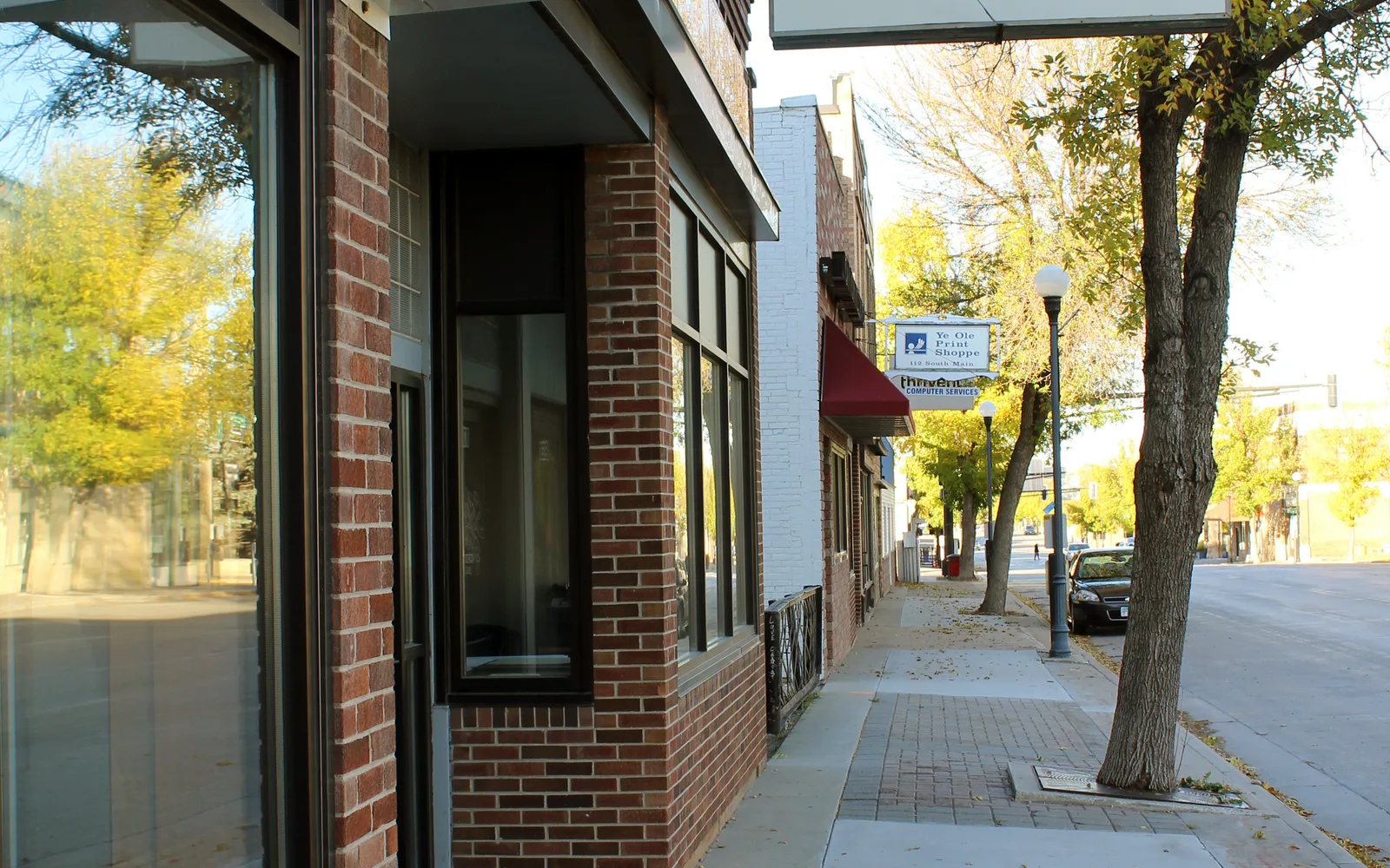 Sidewalk and storefronts on South Main Street showing historic commercial buildings with large windows and traditional architecture
